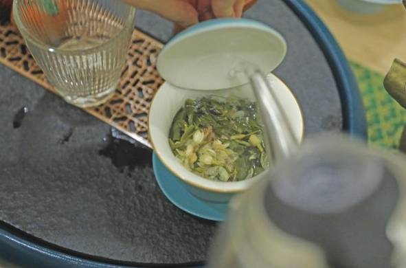 El agua caliente se vierte en la tapa del gaiwan para que caiga suavemente sobre las hojas de té.