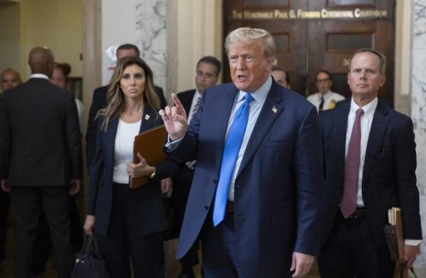 Trump (centro) habla con los periodistas durante un descanso en la sala del tribunal mientras asiste al primer día de su juicio por fraude civil.