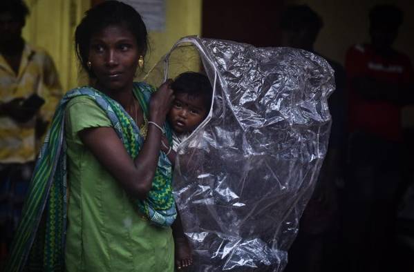 Una mujer y su hijo se cobijan de las fuertes lluvias, este viernes en Chennai (India).