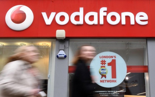Foto de archivo de varios viandantes mientras pasan delante de un establecimiento de la compañía de telecomunicaciones Vodafone en Londres (Reino Unido).