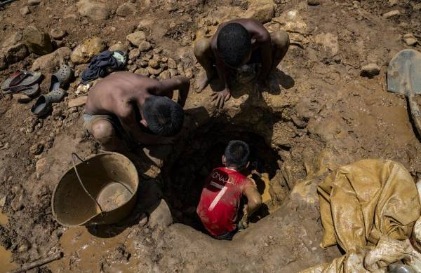Niños mineros venezolanos trabajan cavando en una mina en busca de oro