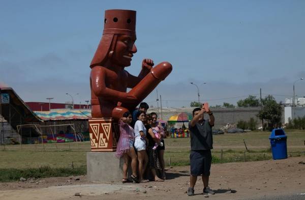 Un grupo de personas posa para una foto frente a una estatua, hoy, en Moche.