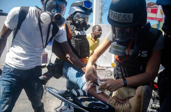 Una periodista extranjera da prímeros auxilios a un fotoperiodista herido en una protesta en Puerto Príncipe (Haití).