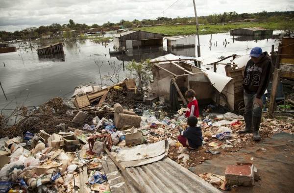 Imagen de archivo que muestra a varias personas cerca a una zona inundada en unos de los campamentos de desplazados de Asunción.