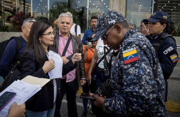 Una mujer explica a miembros de la Policía las razones de la protesta de un grupo de personas hoy, en la entrada del Ministerio de Educación en Caracas, Venezuela.