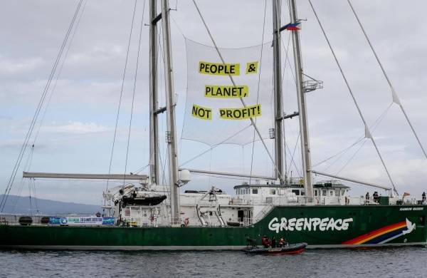 Imagen de archivo de un cartel colgado en los mástiles del barco Rainbow Warrior de Greenpeace en el que se lee íPersonas y Planeta, sin fines de lucro! durante una protesta en una refinería de petróleo.