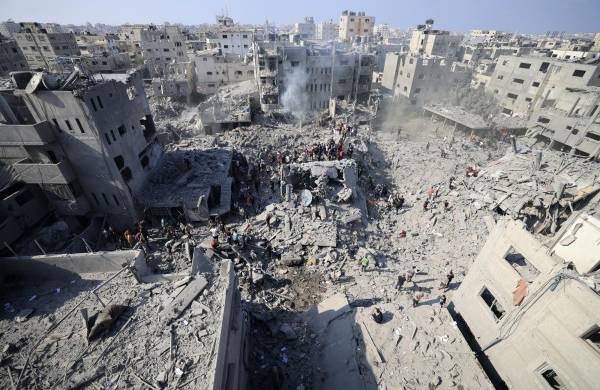 La gente revisa los escombros de los edificios destruidos en un ataque israelí contra el campo de refugiados de Bureij en el centro de la Franja de Gaza el 2 de noviembre de 2023.