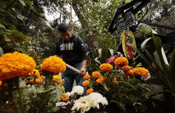 Cientos de personas acuden al Panteón de Xilotepec en la alcaldía de Xochimilco, Ciudad de México, para limpiar y adornar las tumbas de sus difuntos y recibirlos en el Día de Muertos.