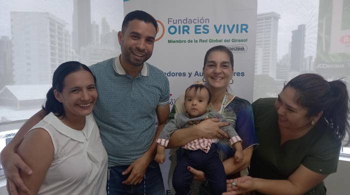 Una familia con la bebé con audífonos beneficiaria de fundación en brazos la presidenta, Giovanna Troncoso.