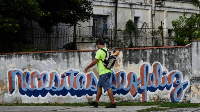 Un hombre camina frente al grafiti.