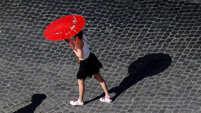 Una mujer porta una sombrilla para protegerse del sol en un caluroso día en Roma.