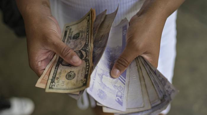 Una mujer cuenta billetes de bolívares y dólares estadounidenses en el barrio de Petare, en Caracas.