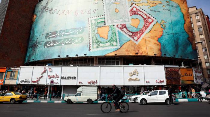 Los coches circulan con tranquilidad junto a un cartel en la plaza Valiasr en la capital iraní.