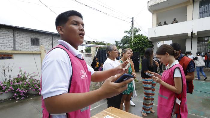 Funcionarios del Consejo Nacional Electoral (CNE) ofrecen información este 9 de febrero de 2025, en un puesto de votación en Olón, Ecuador.