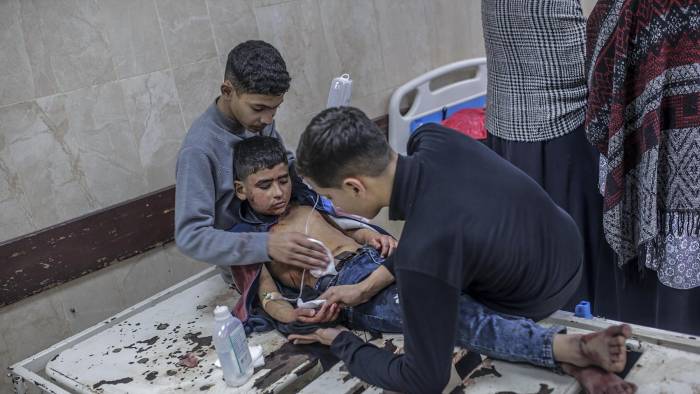 Dos niños ayudan a su hermano pequeño herido en el hospital Al Aqsa tras un ataque aéreo israelí en el campo de refugiados de Al Bureije, en el centro de Gaza.