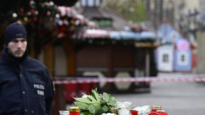 Un policía se encuentra junto a un monumento improvisado en el lugar de un ataque con un coche en un mercado navideño en Magdeburgo, este de Alemania.