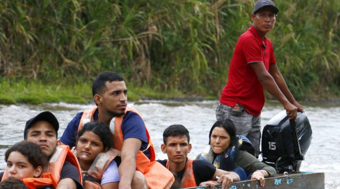 Un grupo de migrantes se transporta en una lancha por el río Turquesa desde el pueblo de Bajo Chiquito, hasta el centro de recepción migratoria de Lajas Blancas.