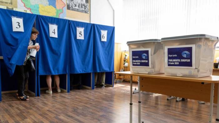 A Moldovan woman walks out of a booth to cast her ballot for the European Parliament elections, at a polling station in Chisinau on June 9, 2024.