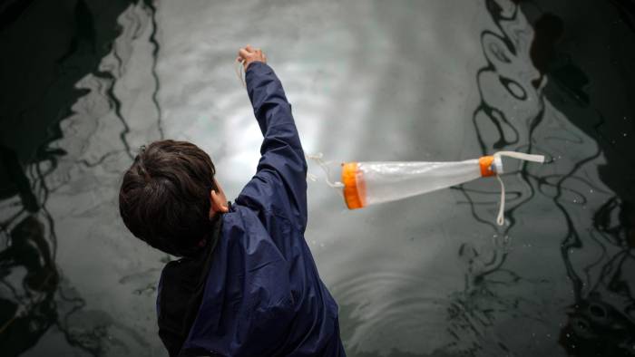 Un niño recoge agua del Port Vell en una de las actividades que con motivo de la Conferencia del Decenio del Océano de la Unesco.