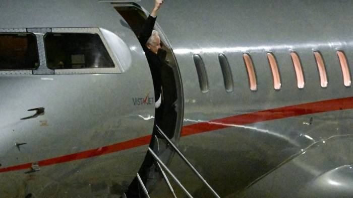 WikiLeaks founder Julian Assange raises his fist from the door of the plane after arriving at Canberra Airport in Canberra on June 26, 2024, after he pleaded guilty at a US court in Saipan to a single count of conspiracy to obtain and disseminate US national defence information. - WikiLeaks founder Julian Assange returned home to Australia to start life as a free man June 26 after admitting he revealed US defence secrets in a deal that unlocked the door to his London prison cell.