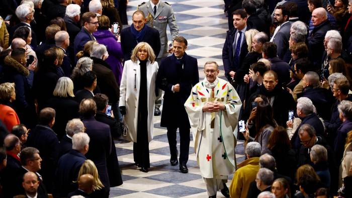 El presidente francés, Emmanuel Macron (D), y su esposa, Brigitte, llegan para asistir a la Misa inaugural, con la consagración del altar mayor, en la Catedral de Notre-Dame.