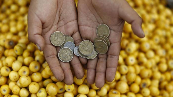 Fotografía de archivo en donde una vendedora de frutas muestra unas monedas en la central de abastos La Tiendona en San Salvador.