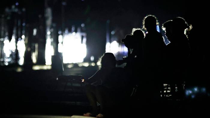 Personas esperan en una calle sin luz este sábado, en La Habana, Cuba.