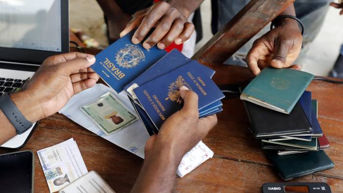 Fotografía de archivo de una persona mientras recibe pasaportes de migrantes de diversas partes del mundo que compran tiquetes para Capurganá, en el embarcadero de Necoclí (Colombia).