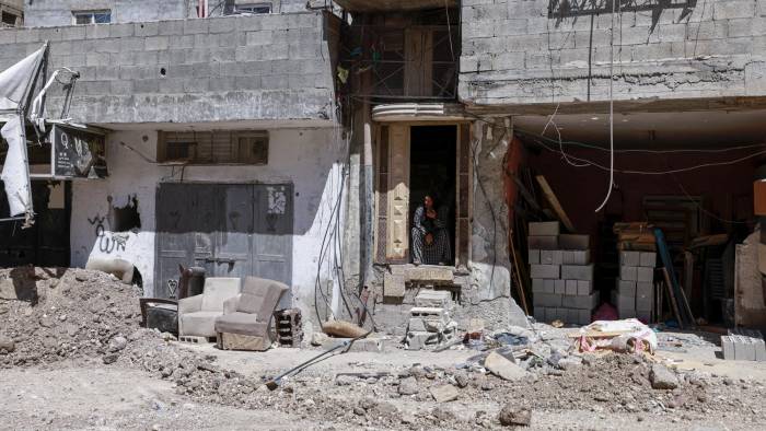 Una mujer observa desde la entrada de su casa, junto a una carretera dañada, tras una redada del ejército israelí en Tulkarem, en la Cisjordania ocupada, el 3 de agosto de 2024.