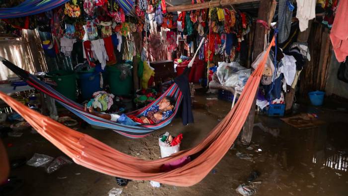 Con el paso de la lluvia, una mujer guna descansa en su hamaca después de poner sus enseres sobre palos o bolsa de plástico.