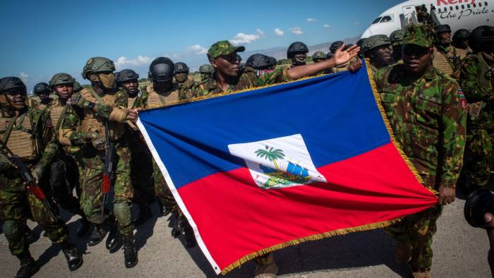 Policías kenianos sostienen una bandera de Haití a su llegada al aeropuerto internacional Toussaint Louverture este sábado, en Puerto Príncipe (Haití).