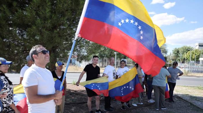 Venezolanos sostienen banderas durante la llegada de Edmundo González Urrutia al aeropuerto militar de Torrejón de Ardoz en Madrid