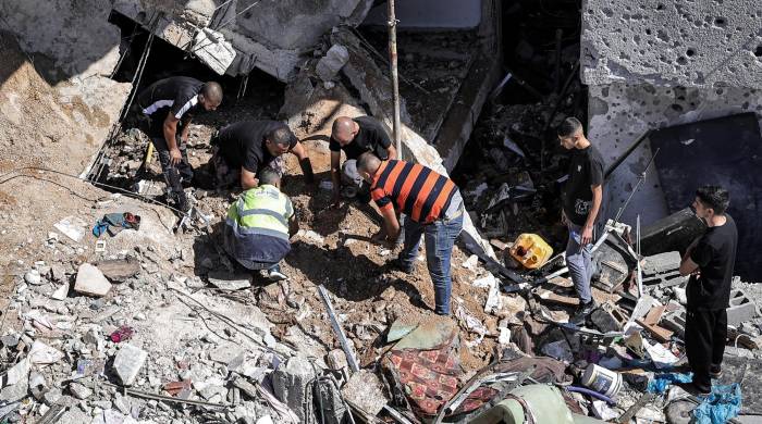 La gente busca entre los escombros de un edificio golpeado por un bombardeo en el campamento de refugiados palestinos de Nur Shams.