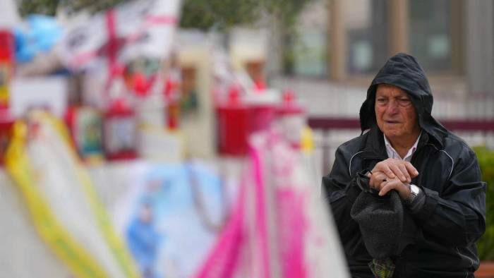 Un hombre reza a los pies de una estatua de Juan Pablo II en el Hospital Gemelli, donde el papa Francisco está hospitalizado por neumonía.