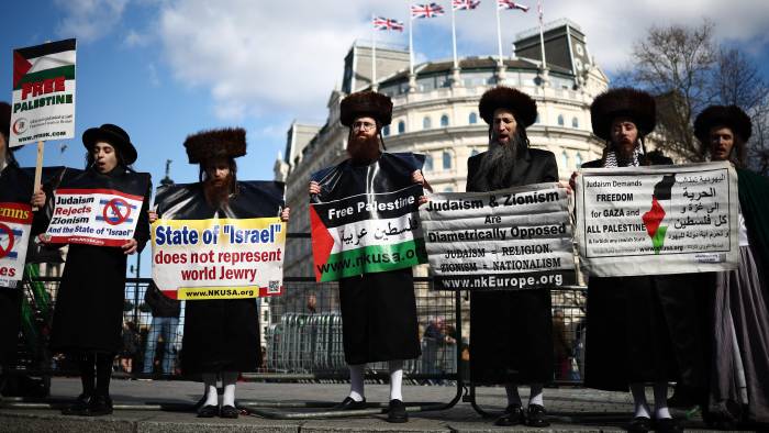 Miembros de la comunidad judía ultraortodoxa que apoyan la causa palestina posan con pancartas durante una marcha pro palestina en el centro de Londres, el 15 de marzo de 2025, exigiendo el fin del asedio israelí a Gaza y los ataques contra los palestinos en Cisjordania.