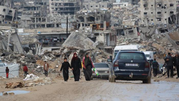 Palestinos desplazados caminan por un camino embarrado en medio de la destrucción en Jabalia, en el norte de la Franja de Gaza.