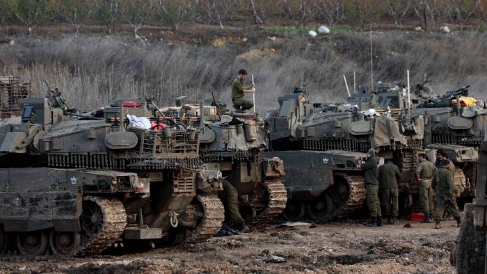 Soldados israelíes pasan junto a tanques estacionados en un campo al regresar a Israel tras un alto el fuego con Hizbulá, en Metula, en el norte de Israel.