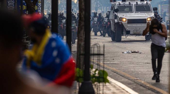 Manifestantes corren durante enfrentamientos entre opositores y miembros de la Guardia Nacional Bolivariana (GNB).