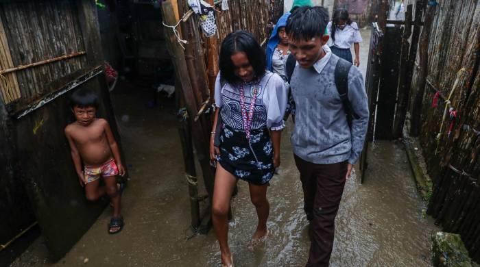 Niños y jovenes de la isla Gardí Sugdub caminan bajo la lluvia y sobre charcos para llegar a sus hogares.