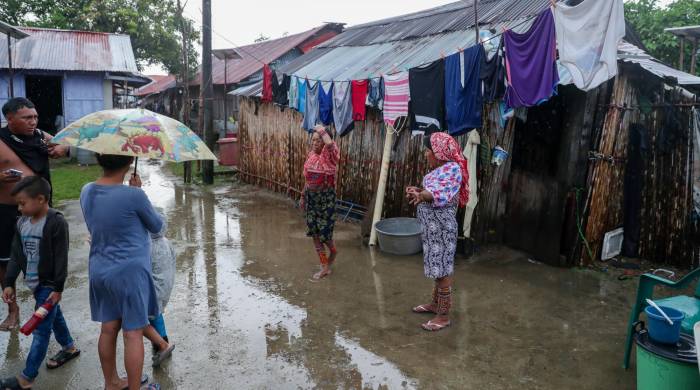 Familias de la isla Gardí Sugdub hablan mientras la lluvia para y deja a su paso charcos por todos los caminos.