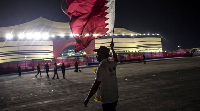 Un hombre sostiene una bandera de Catar antes de un evento deportivo.