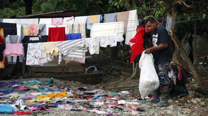 Un hombre recoge ropa en el poblado de Imias tras el paso de una tormenta tropical.