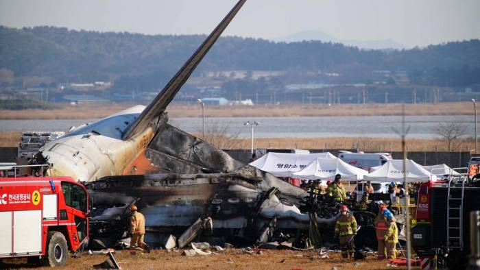 El personal de rescate trabaja cerca de la sección de la cola de un avión Boeing 737-800 de Jeju Air después de que la aeronave se estrellara y se incendiara en el Aeropuerto Internacional de Muan.