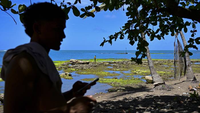 Migrantes venezolanos permanecen en la playa mientras esperan un bote que los lleve a Colombia en Miramar, cerca de Palenque.