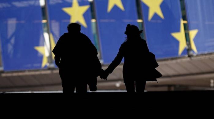 Pedestrians walk past a banner in the EU colours, displayed on the building of the European Parliament in Brussels during European Parliament elections on June 9, 2024.