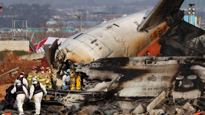 Los bomberos trabajan en los restos del avión Jeju Air siniestrado este domingo en el aeropuerto surcoreano de Muan.