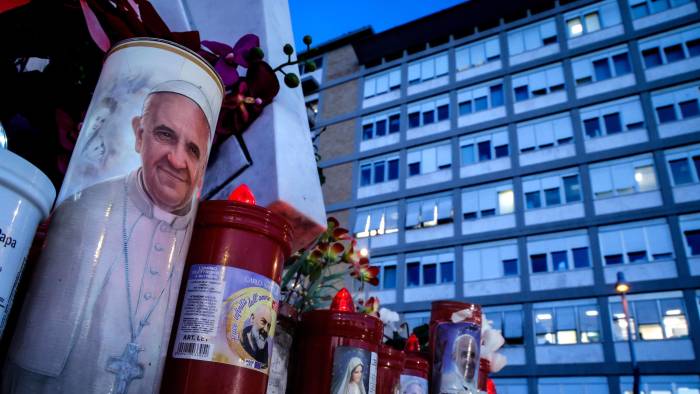 Una vela con la imagen del Papa Francisco, al pie de la estatua de San Juan Pablo II en las afueras del Hospital Universitario Gemelli, en Roma.