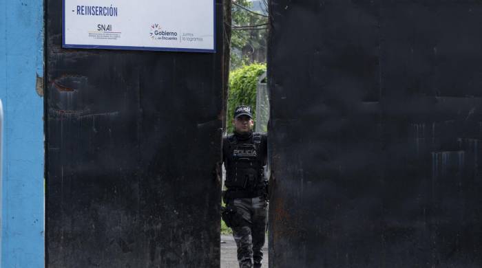 Miembro de la Policía Nacional Ecuatoriana cerrando la puerta del complejo penitenciaro Del Litoral.
