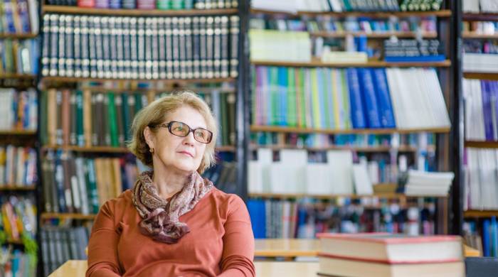 Happy relaxing or dreaming senior woman in library