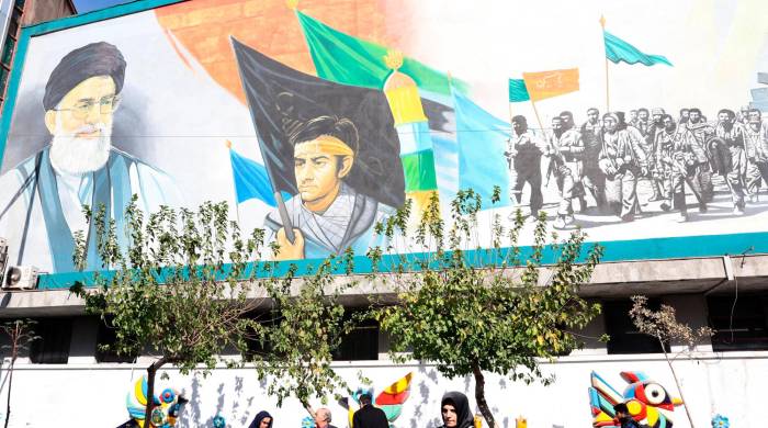 Iraníes caminan junto a un mural del líder supremo iraní, el ayatolá Ali Khamenei, en Teherán.